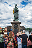 Tourists touching a plaque that is part of the statue St. John of Nepomuk for good luck, Prague.