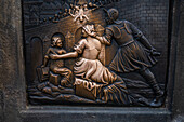 Tourists touching a plaque that is part of the statue St. John of Nepomuk for good luck, Prague.