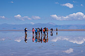 Tourists walking on the Salinas Grandes salt flats on the altiplano in Argentina. Recent rains left a shallow sheet of water on the flats.