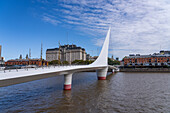 La Puente de la Mujer oder die Frauenbrücke über das Dock 3 in Puerto Madero, Buenos Aires, Argentinien. Dahinter befindet sich das Libertador-Gebäude, der Sitz des Verteidigungsministeriums