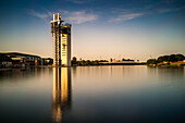 The Schindler Tower, designed by Guillermo Vazquez Consuegra, stands by the Guadalquivir River in Seville, Spain. Captured at sunset, the scene evokes serenity and modern architectural elegance.