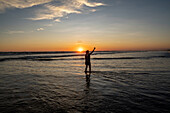 Sunset on the beach in Las Lajas, Panama. Person stands on the beach silhouetted.