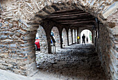 Wander through the charming stone arcade of Plaza Mayor in Yanguas, where history meets vibrant local life in Soria, Spain.