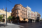 Seville, Spain, Sep 30 2009, This vibrant street in Seville features the red brick Seville Tourist Office and the Seguros Santa Lucia building amidst lively city life.