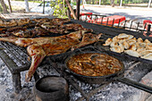 Locro, a traditional stew, & chivo or young goat cooking over the coals in a parrilla in Termas de Rio Hondo, Argentina.