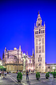 Visitors admire the stunning architecture of the Giralda tower against a twilight sky in Seville, capturing the essence of Andalusian culture.