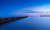 Serene twilight scene capturing the tranquil waters of Almeria port mouth viewed from Zapillo Beach. Features a long exposure for smooth water effect under a vibrant dusk sky in Andalucia, Spain.