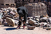 A stone mason shapes a stone with a hammer and chisel at a construction project in Tilcara, Argentina.