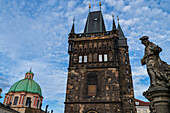 Statue des Heiligen Ivo von Kermartin und alter Turm an der Karlsbrücke in Prag