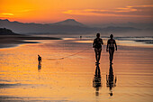 Sonnenuntergang am Strand von Santa Lucía, Panama. Menschen gehen am Strand spazieren, die Silhouette ist zu sehen