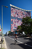 Berlin, Germany, July 27 2009, A cyclist rides along the street adjacent to the colorful GSW Building in Kreuzberg, showcasing modern architecture under a clear sky.