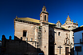 Explore the stunning Convent of Descalzas in Carmona, showcasing beautiful Mediterranean architecture against a clear blue sky.