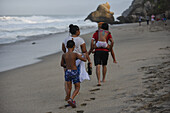 Playful family walking on the beach in front of Finca Barlovento, Tayrona National Park, Colombia