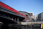 A regional train approaches Friedrichstrasse station in Berlin, showcasing the vibrant urban landscape on a clear day.