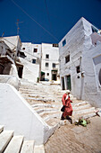 A woman walks down the steps of a charming whitewashed alley in Tetouans historic Medina, showcasing the vibrant local architecture.