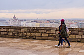 Couple walking with Parliament building and Danube River behind, Budapest, Hungary, Europe