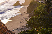 Couple walking on the beach in front of Finca Barlovento at sunset, Tayrona National Park, Colombia