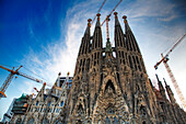 The intricate facades of Gaudís Sagrada Familia rise majestically, showcasing ongoing construction against a stunning sky.