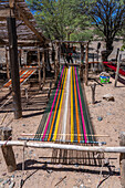 Colorful yarn on a wooden foot loom outside in a home weaving workshop in Seclantas, Argentina in the Calchaqui Valley.