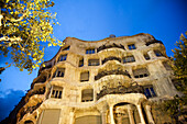 Explore the stunning architecture of Gaudi's La Casa Mila, beautifully lit up on a night in Barcelona, highlighting its unique design on the Paseo de Gracia.