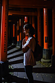 Young caucasian woman praying at Fushimi Inari Taisha temple at night, Kyoto, Japan