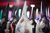 Colorful nazareno figures adorn a shop specializing in Semana Santa items in Seville, showcasing local traditions.