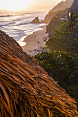 Young woman walking on the beach in front of Finca Barlovento at sunset, Tayrona National Park, Colombia