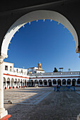 Discover the vibrant market square in Carmona, where whitewashed walls and arches create a stunning backdrop under a clear blue sky.