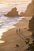 Couple walking on the beach in front of Finca Barlovento at sunset, Tayrona National Park, Colombia