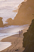 Couple walking on the beach in front of Finca Barlovento at sunset, Tayrona National Park, Colombia