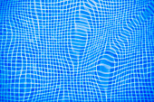 Gentle ripples and reflections create a captivating pattern in the blue tiled water of a swimming pool.