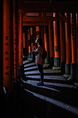 Young caucasian woman praying at Fushimi Inari Taisha temple at night, Kyoto, Japan