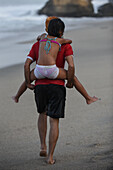 Playful family walking on the beach in front of Finca Barlovento, Tayrona National Park, Colombia