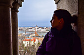 Young woman enjoying the view of Parliament building, Chain Bridge and Danube River through old columns, Budapest, Hungary, Europe