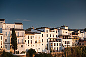 Charming whitewashed houses cling to the cliffs of El Tajo gorge in the beautiful town of Ronda during golden hour.