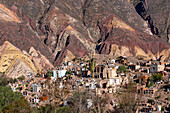 Gräber auf dem Friedhof Unsere Liebe Frau von Carmen in Maimara im Humahuaca-Tal oder Quebrada de Humahuaca, Argentinien. Dahinter befindet sich die Painter's Palette, eine farbige geologische Antiklinale