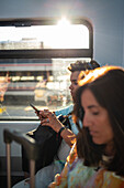 Travelers using smartphone in train to airport at sunset, Madrid