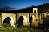 The Alcántara Bridge majestically spans the Tagus River at twilight, highlighting its historic architecture and serene beauty.