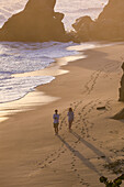 Couple walking on the beach in front of Finca Barlovento at sunset, Tayrona National Park, Colombia