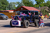 A Jeep decorated with American flags in the Fourth of July Parade on Independence Day in Moab, Utah. A woman throughs candy to the crowd.