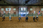 Cowgirls in a mounted drill team perform with flags at the beginning of the Moab Junior Rodeo in Moab, Utah.