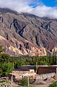 A traditional adobe farm house in front of the Painter's Palette in the Humahuaca Valley or Quebrada de Humahuaca in Argentina.