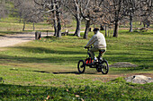 A man driving an electric tricycle in La Herrería Park of San Lorenzo de El Escorial, Madrid.