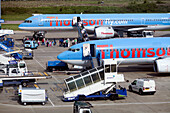 London, UK, May 3 2009, Passengers board Thomson company planes while luggage is loaded at Luton Airport, showcasing airline operations in action.