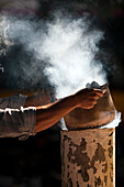 A street vendor tends to roasting chestnuts in Seville, filling the air with a warm, inviting scent on a sunny afternoon.