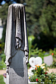 Berlin, Germany, July 27 2009, The elaborate obelisk of Theodor Döring stands in Jerusalem Cemetery, adorned with a cloaked figure amidst lush greenery.