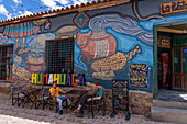 Tourists sit in front of a colorful mural on a restaurant in Humahuaca in the Quebrada de Humahuaca, Argentina.