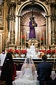 Seville, Spain, March 4 2008, A couple exchanges vows in a wedding ceremony at Señor del Gran Poder altar in Seville, surrounded by candles and floral arrangements.