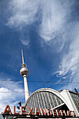 Das Bahnhofsschild des Alexanderplatzes ragt mit dem Fernsehturm in den strahlend blauen Himmel in Berlin, Deutschland