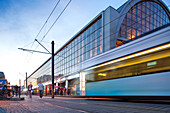 A tram pulls into Alexanderplatz, showcasing the vibrant atmosphere of Berlin during the evening rush.